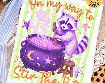 May include: A white t-shirt featuring a purple raccoon stirring a purple cauldron with a wooden spoon. The text reads On my way to Stir The Pot. The background has light green vertical stripes, purple stars, and a yellow crescent moon.