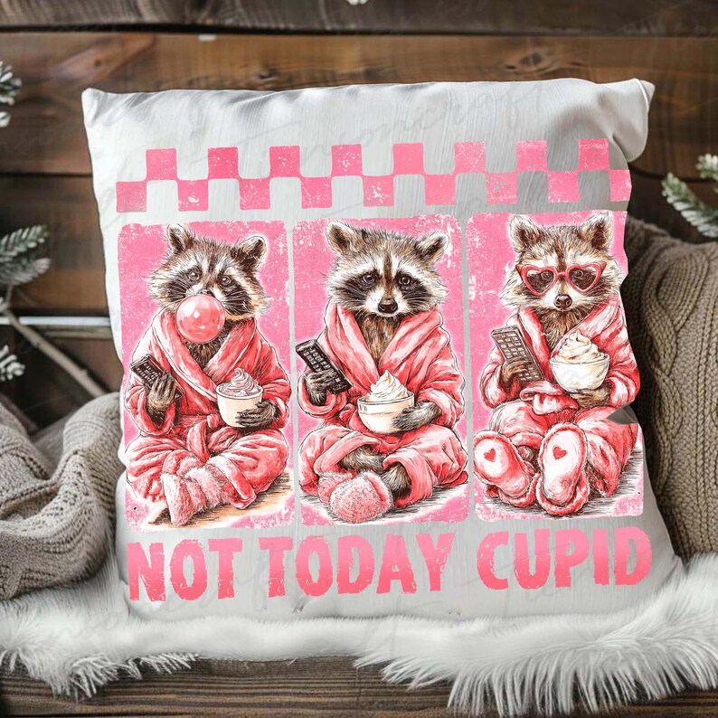 May include: White square pillow with a pink and gray graphic of three raccoons in pink robes, each holding a remote and a dessert. The text "NOT TODAY CUPID" is printed in pink at the bottom of the pillow.