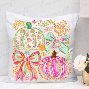 May include: White decorative pillow featuring colorful pumpkins and bows. The pumpkins are in shades of pink, orange, and green, with floral and leaf patterns. The bows are in bright pink, orange, and teal with gold glitter accents. Floral accents complete the design.