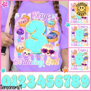 May include: A light purple t-shirt featuring a large turquoise number three with a gold glitter outline. The design includes cartoon dumplings with faces, pink and blue stars, and the text Kayce Birthday Girl in a cursive font.
