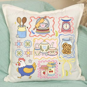 Puede incluir: Un coj&iacute;n decorativo con un dise&ntilde;o de patchwork que presenta ilustraciones con tem&aacute;tica de cocina. Las im&aacute;genes incluyen un rodillo, tazas de t&eacute;, una balanza, un tarro de galletas, una gallina y tarros de mermelada. La paleta de colores es suave, con tonos pastel de azul, rosa y amarillo.