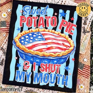 May include: A black canvas with the words "Sweet Potato Pie & I Shut My Mouth" in red and blue. The pie is decorated with the American flag. The image has a patriotic theme.