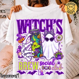 Op de afbeelding: Een wit t-shirt met een grafische print met de tekst "WITCH'S BREW social club". Het ontwerp bevat een skeletthand die een drankblikje vasthoudt, een geest met een luipaardprint strik en zonnebril, een pompoen, een lantaarn en vleermuizen.