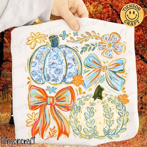 May include: White fabric with a colorful fall-themed design. The design includes pumpkins, bows, and floral elements in shades of blue, orange, and gold. The text "tiensoncraft" is visible at the bottom.