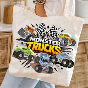 May include: A cream tote bag with a vibrant monster truck design. The graphic showcases several monster trucks in orange, green, yellow, blue, and light blue, accompanied by checkered flags and the text "MONSTER TRUCKS" in yellow and orange.