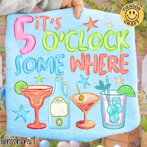 May include: A light blue sign with the phrase "It's 5 O'Clock Somewhere" in pink, green, and orange. The sign features illustrations of cocktails, a milk bottle, and stars. A yellow smiley face logo is in the upper right corner.