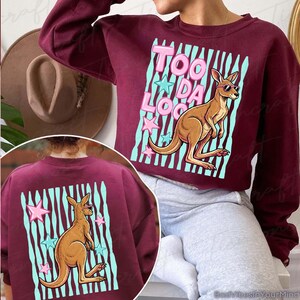 May include: A burgundy sweatshirt with a kangaroo wearing sunglasses and the text "Too Da Loo" in pink. The kangaroo is set against a light blue striped background with pink and blue stars. The back of the sweatshirt also features the kangaroo design.