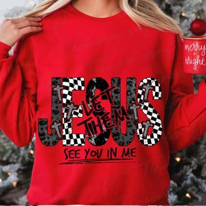 May include: A red sweatshirt with the words "JESUS LET THEM SEE YOU IN ME" in a black and white checkered and leopard print design. The sweatshirt also features small cross graphics.