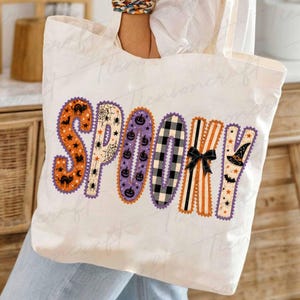 Może przedstawiać: Biała torba pł&oacute;cienna z napisem SPOOKY wykonanym dużymi, ozdobnymi literami. Każda litera ma unikalny wz&oacute;r, w tym pomarańczowe koty, pajęczyny, fioletowe dynie, czarno-białą kratę, pomarańczowe paski oraz czarny kapelusz czarownicy.