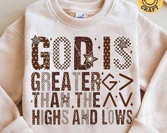 May include: A beige sweatshirt with the text "GOD IS GREATER THAN THE HIGHS AND LOWS" in brown, checkered, and star-patterned letters. The sweatshirt has a crew neck and long sleeves. The brand name "tiensoncraft" is printed at the bottom.
