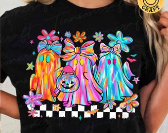 May include: A black t-shirt featuring a graphic of three colorful ghosts wearing large bows. The ghosts are orange, pink, and blue, with one holding a jack-o'-lantern bucket. The design includes flowers, stars, bats, and a black and white checkered base.