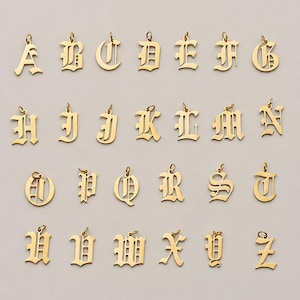 Op de afbeelding: Een collectie van zesentwintig goudkleurige metalen letterbedels, elk voorzien van een sierlijk gotisch lettertype in Oud-Engelse stijl. Elke individuele letterhanger heeft een klein rond ringetje aan de bovenkant voor bevestiging.