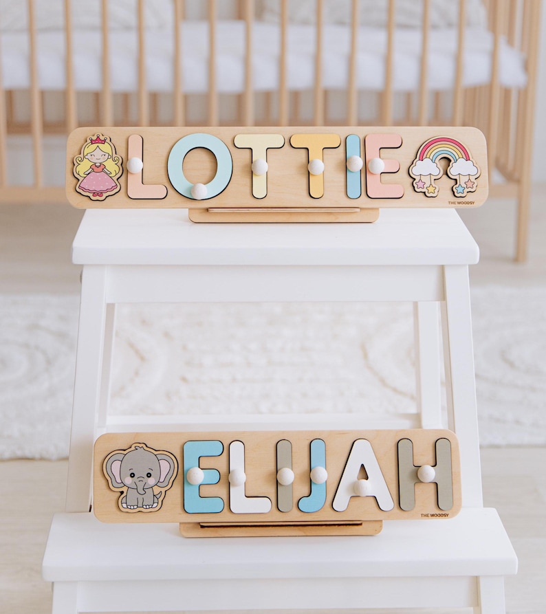 Pu&ograve; includere: Due puzzle di nomi in legno per bambini, con i nomi "Lottie" ed "Elijah". Il puzzle "Lottie" presenta una principessa e un arcobaleno, mentre il puzzle "Elijah" ha un elefante. Ogni puzzle ha lettere colorate e pioli.