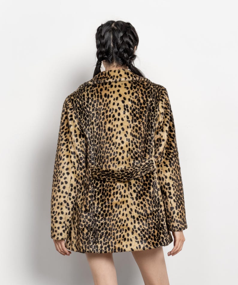 May include: A faux fur coat with a leopard print pattern. The coat features a notched collar, long sleeves, and a matching belt. The coat's colors include tan, brown, and black.