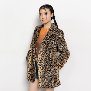 May include: A leopard print faux fur coat with a classic lapel collar. The coat features a brown and black spotted pattern. The model is wearing an orange sequined top and green shorts. The coat has pockets.