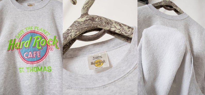 May include: A light gray crewneck sweatshirt featuring an embroidered Hard Rock Cafe St. Thomas logo in neon green, blue, and red. The front graphic reads Save The Planet Hard Rock Cafe St. Thomas. The interior tag indicates size X-Large.