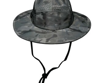 May include: A gray and black camouflage bucket hat with a black adjustable chin strap. The hat has a breathable mesh panel on the top.