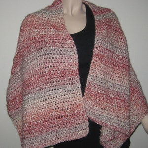 May include: A crocheted shawl in shades of red, pink, and beige. The shawl is made with a simple stitch pattern and has a fringed edge.