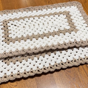 Puede incluir: Dos manteles individuales de ganchillo en un patrón de cuadrado de la abuela marrón y blanco.