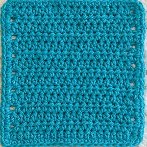 May include: A square-shaped, bright turquoise crochet piece featuring a consistent, dense stitch pattern. The edges are defined by a series of evenly spaced, small rectangular openings that create a border around the solid, textured center.