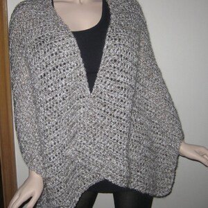 May include: A gray and white crocheted cardigan with a V-neck and long sleeves.