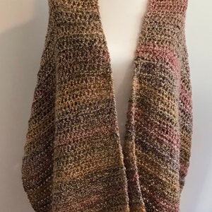 Op de afbeelding: Een gestreepte gebreide sjaal in bruin, roze en beige, gedrapeerd over een wit mannequin.