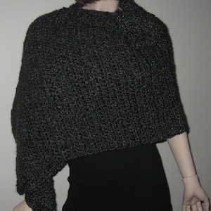 May include: A black knitted poncho with a high neck and a slightly asymmetrical hem.