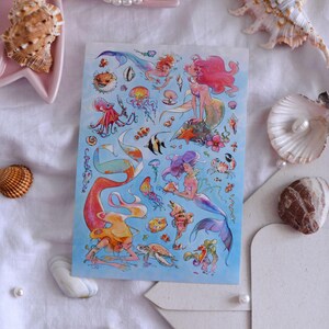 Puede incluir: Una hoja de pegatinas con ilustraciones de sirenas y criaturas marinas. El dise&ntilde;o incluye sirenas con pelo rosa, morado y naranja, junto con peces, medusas y otra vida marina. El fondo es de color azul claro.