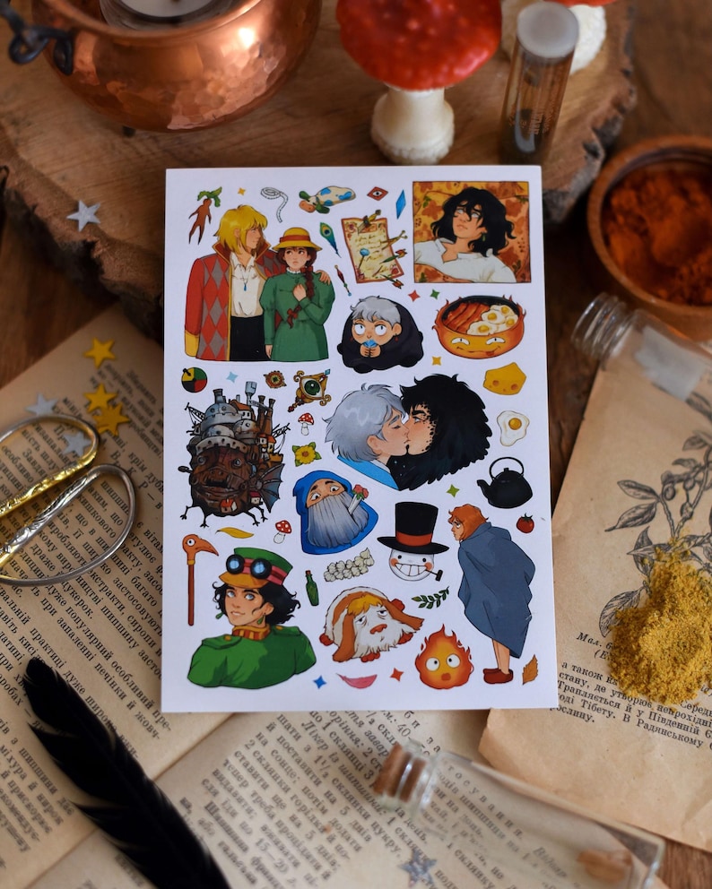 May include: A sticker sheet featuring illustrations of characters and scenes from a popular animated film. The stickers depict various characters, food, and objects in a colorful and detailed style. The sheet is on a wooden surface with other decorative items.