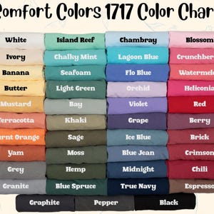 May include: A Comfort Colors 1717 color chart displaying a grid of folded t-shirts in various shades. The text reads Comfort Colors 1717 Color Chart, followed by labels for colors including White, Ivory, Banana, Butter, Mustard, Terracotta, Burnt Orange, Yam, Grey, Granite, Island Reef, Chalky Mint, Seafoam, Light Green, Bay, Khaki, Sage, Moss, Hemp, Blue Spruce, Chambray, Lagoon Blue, Flo Blue, Orchid, Violet, Grape, Ice Blue, Blue Jean, Midnight, True Navy, Blossom, Crunchberry, Watermelon, Heliconia, Red, Berry, Brick, Crimson, Chili, Espresso, Graphite, Pepper, and Black.