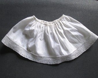 May include: White cotton petticoat with a lace trim. The petticoat is gathered at the waist and has a scalloped edge.