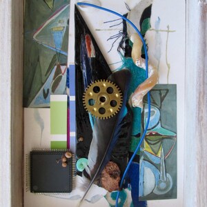May include: A mixed media artwork in a wooden frame. The artwork features a blue feather, a gold gear, and various blue, green, and white paper scraps. The artwork is abstract and has a whimsical feel.