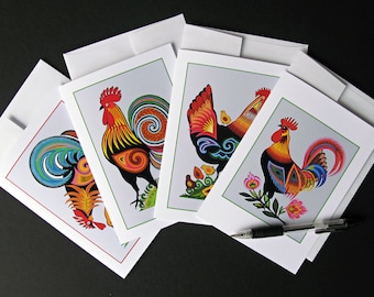May include: Set of four greeting cards featuring colorful rooster illustrations. Each card has a different rooster design with intricate details and vibrant colors like red, yellow, blue, and green.
