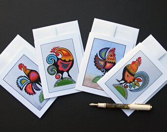 May include: Four blank greeting cards with colorful rooster illustrations. Each card features a different rooster design with intricate details and vibrant colors.