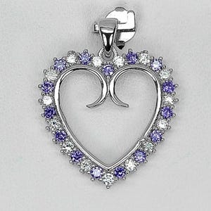 以下が含まれることがあります： 白と紫の宝石のハローが付いた、銀色のハート型のペンダント。ペンダントの上部にはチェーン用のベイルが付いています。ハートのデザインは中央が開いており、上部に装飾的な装飾が施されています。