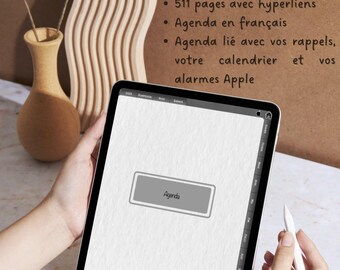 Puede incluir: Una tableta digital blanca con un botón gris que dice "Agenda". La tableta está siendo sostenida por las manos de una persona. El fondo es una superficie de madera marrón con el texto "AGENDA NUMÉRIQUE 2025" y viñetas que describen las características de la agenda digital.