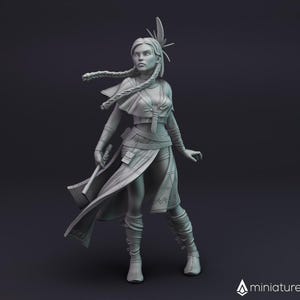 Puede incluir: Una miniatura impresa en 3D de color gris de una figura femenina que lleva una túnica fluida y sostiene un arma. Tiene el pelo largo y un tocado de plumas.