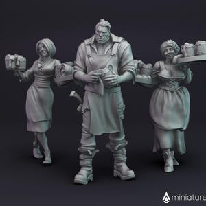 Peut inclure: Trois figurines miniatures, un homme et deux femmes, habillés en costumes médiévaux, tenant des chopes de bière. L'homme porte un tablier en cuir brun et une chemise sombre. Les femmes portent de longues robes avec des tabliers. Les figurines sont debout sur une base en bois.