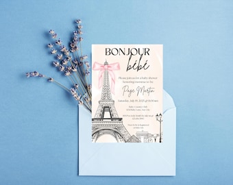 May include: A baby shower invitation featuring the Eiffel Tower with a pink bow, the words "Bonjour Bébé", and event details. The invitation is in a light blue envelope with lavender sprigs on a blue background.