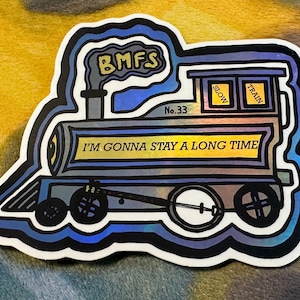 May include: A blue and yellow train sticker with the text "BMFS" on the smoke stack and "I'm gonna stay a long time" on the side. The train has a number "33" on the side and the words "Slow" and "Train" on the windows.