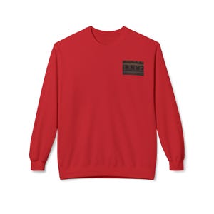 May include: A bright red crew neck sweatshirt. A small, rectangular image is printed on the upper left chest area. The sweatshirt has long sleeves and a classic, casual design. This garment is suitable for everyday wear.