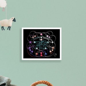 Op de afbeelding: Een ingelijst kunstwerk met een zwarte achtergrond toont een kleurrijk, abstract ontwerp met het woord 'HUSH' in het midden. Het kunstwerk wordt getoond in een kinderkamer, met een rieten wieg en hangende schaapdecoraties.