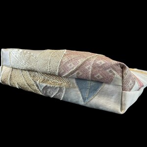 May include: A beige fabric clutch bag with a colorful embroidered design featuring geometric shapes and floral patterns.