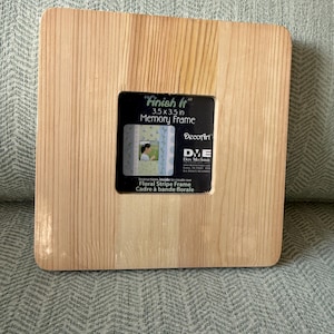 May include: A square, unfinished wooden memory frame with a 3.5 x 3.5 inch opening. The frame has a natural wood grain and includes a black label with the text "Finish It" and "Memory Frame". The frame is designed to create a floral stripe frame.