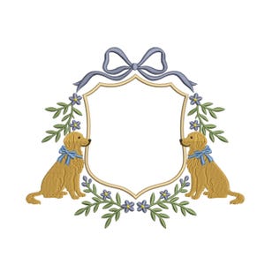 May include: Embroidered design featuring two golden retriever dogs with blue bows, flanking a shield-shaped frame. The frame is adorned with floral and leaf accents, and a blue bow at the top. The design is on a white background.