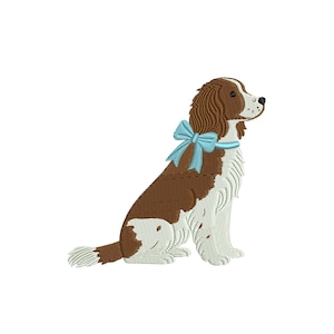 Op de afbeelding: Geborduurd ontwerp van een Cavalier King Charles Spaniel hond, zittend en naar rechts kijkend. De hond heeft bruine en witte vacht, met een lichtblauwe strik om zijn nek. De achtergrond is wit.