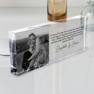 May include: A clear glass block with a black and white photo of a mother and child. The text "The Heart of Our Home" is inscribed on the block, along with the names "Elizabeth & Olivia".