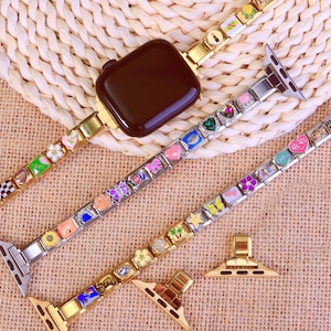 以下が含まれることがあります： カラフルなチャームが付いた、いくつかの装飾的なApple Watchバンド。バンドはゴールド、シルバー、ローズゴールドで、花、ハート、その他のデザインのチャームが付いています。黒いApple Watchがバンドの1つに取り付けられています。