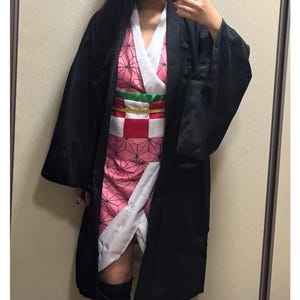 May include: A cosplay costume with a black overcoat, a pink patterned kimono, and a red and white checkered obi belt. The costume has a white collar and accents, with a green and gold belt. The outfit is designed for cosplay events.