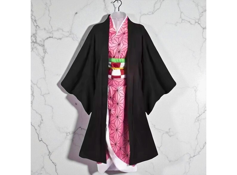 May include: A black kimono-style robe with wide sleeves, layered over a pink patterned garment. The pink garment features a geometric design. A colourful obi belt with red, white, and green accents cinches the waist. The outfit is displayed on a hanger.
